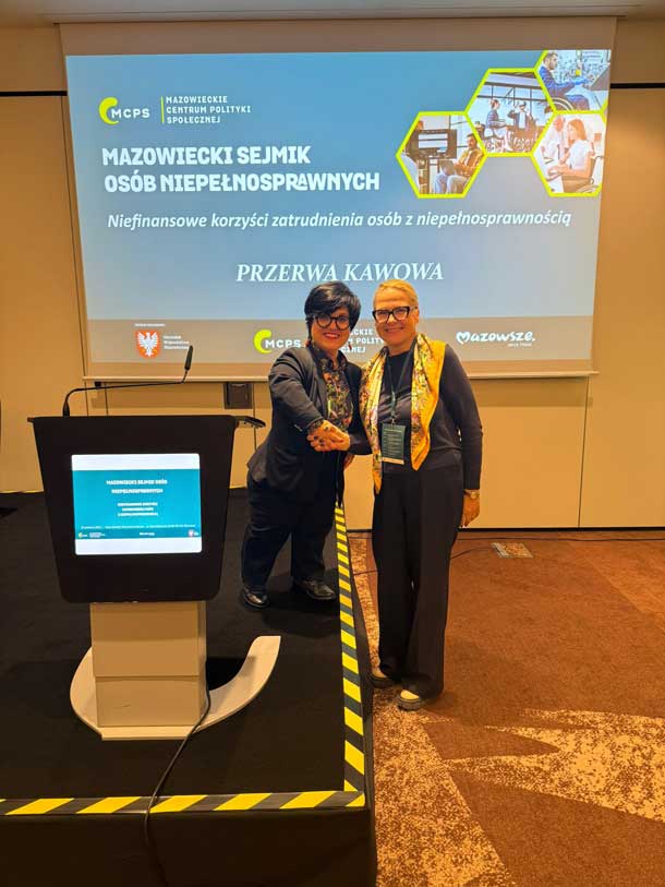 Justyna Cuże i inna kobieta stoją przy mównicy na tle ekranu z tytułem konferencji o aktywności zawodowej osób z niepełnosprawnościami.