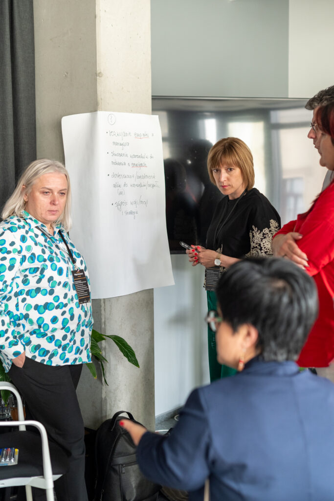 Grupa czterech osób omawia pomysły przy flipcharcie z notatkami.